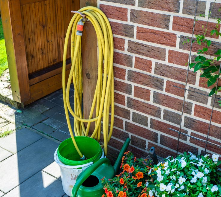 Wasserschlauch mit Gartenschlauch-Adapter am Wasserhahn befestigt