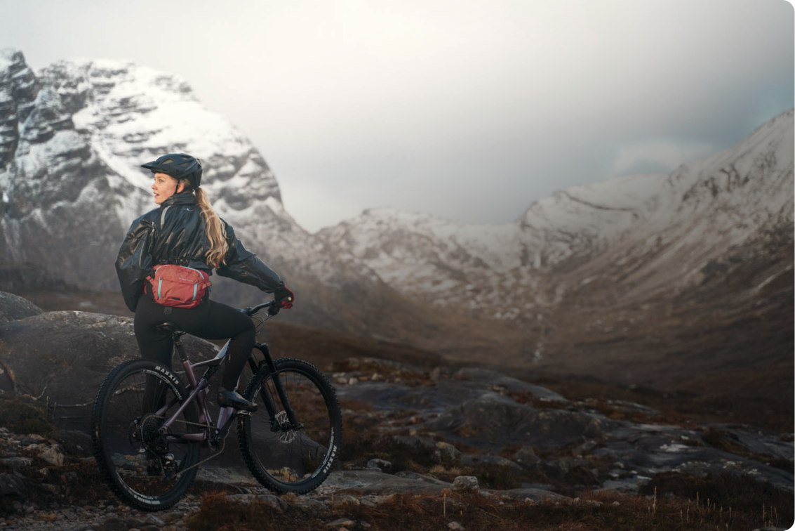 Eine Frau sitzt auf einem Mountainbike, umgeben von schneebedeckten Bergen