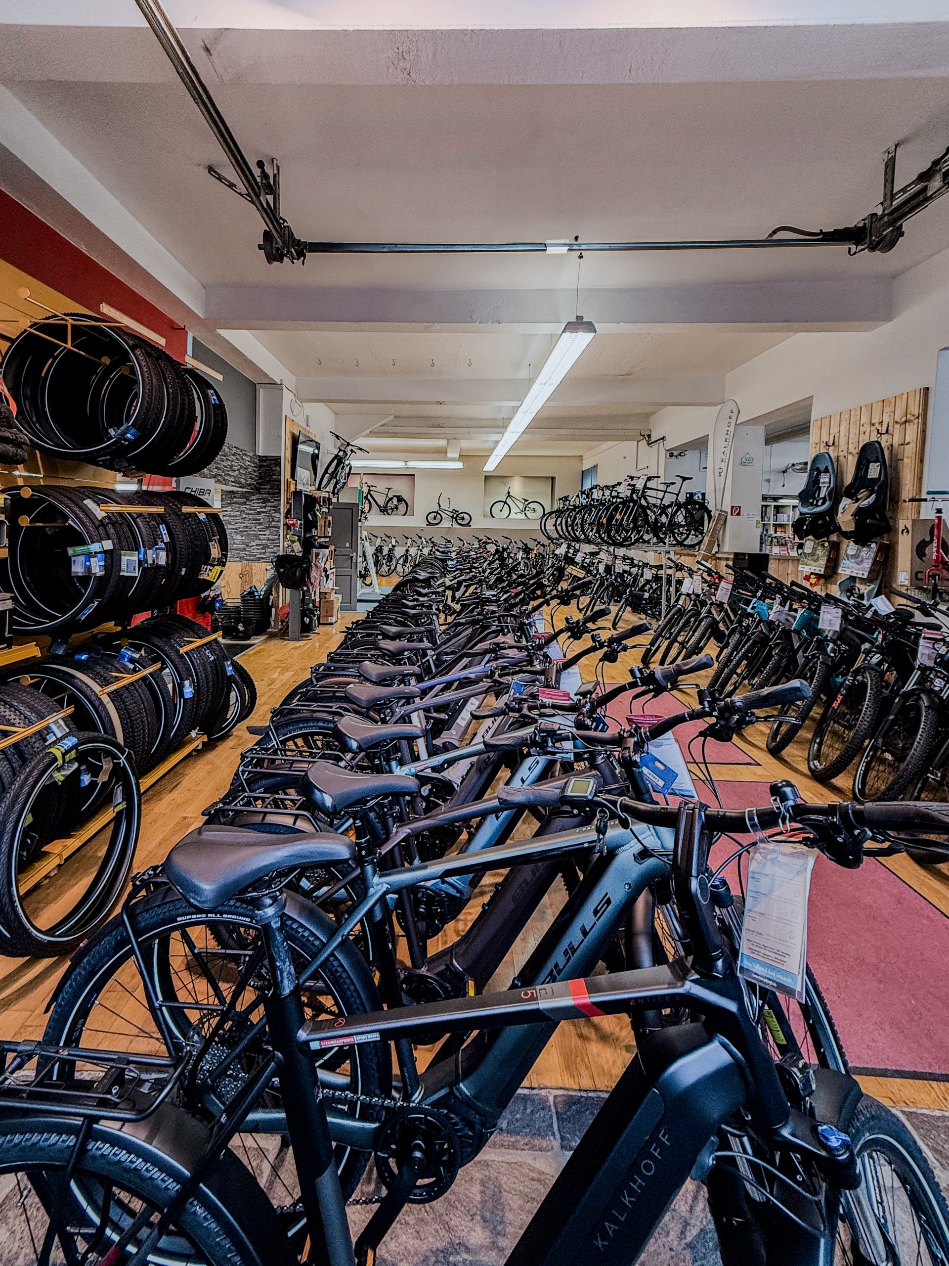 Innenansicht der Fahrradprofis-Filiale Biberach mit einer langen Reihe ausgestellter E-Bikes und Reifen im Regal