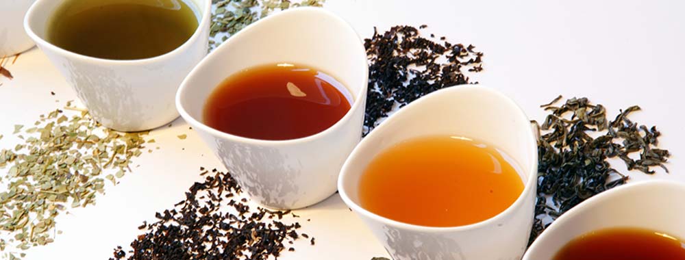 verschiedene Tees in weißen Teeschalen
