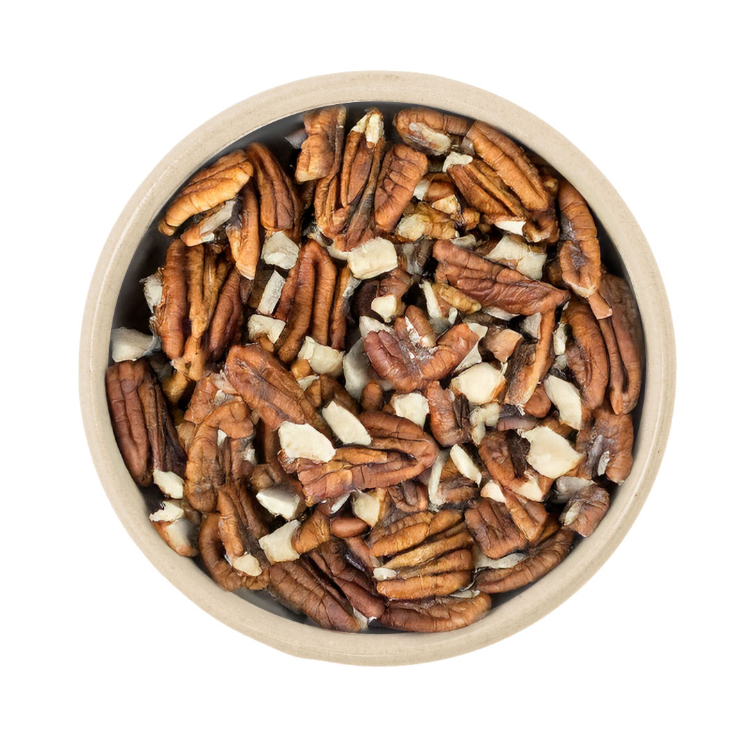 Gehackte und halbierte Pekannusskerne (Pecan) in runder Schüssel auf weißem Hintergrund