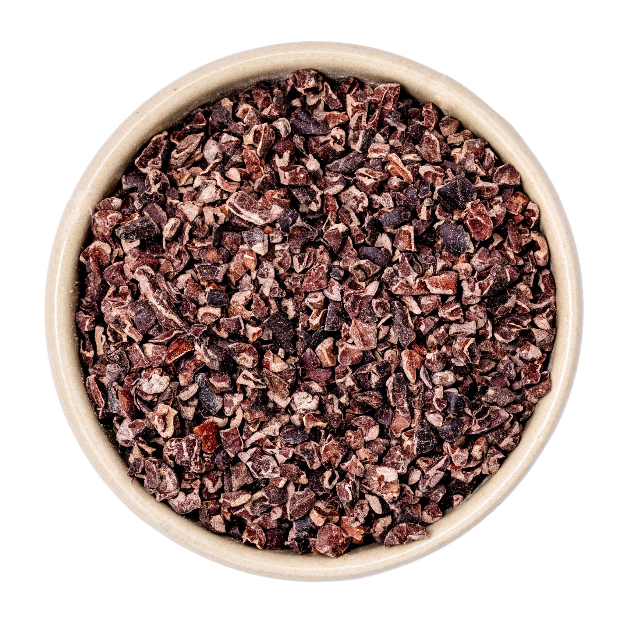 Keramikschüssel mit grob gehackten Kakaonibs, Nahaufnahme auf weißem Hintergrund