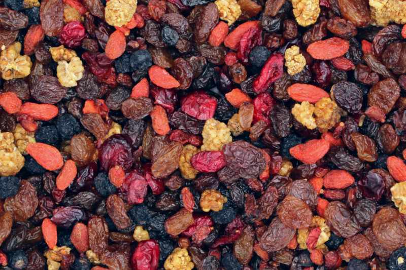 Nahaufnahme eines bunten Trockenfrüchte-Mixes mit Rosinen, getrockneten Beeren, Gojibeeren und Maulbeeren; ideal als Snack oder Zutat für Müsli und Backwaren
