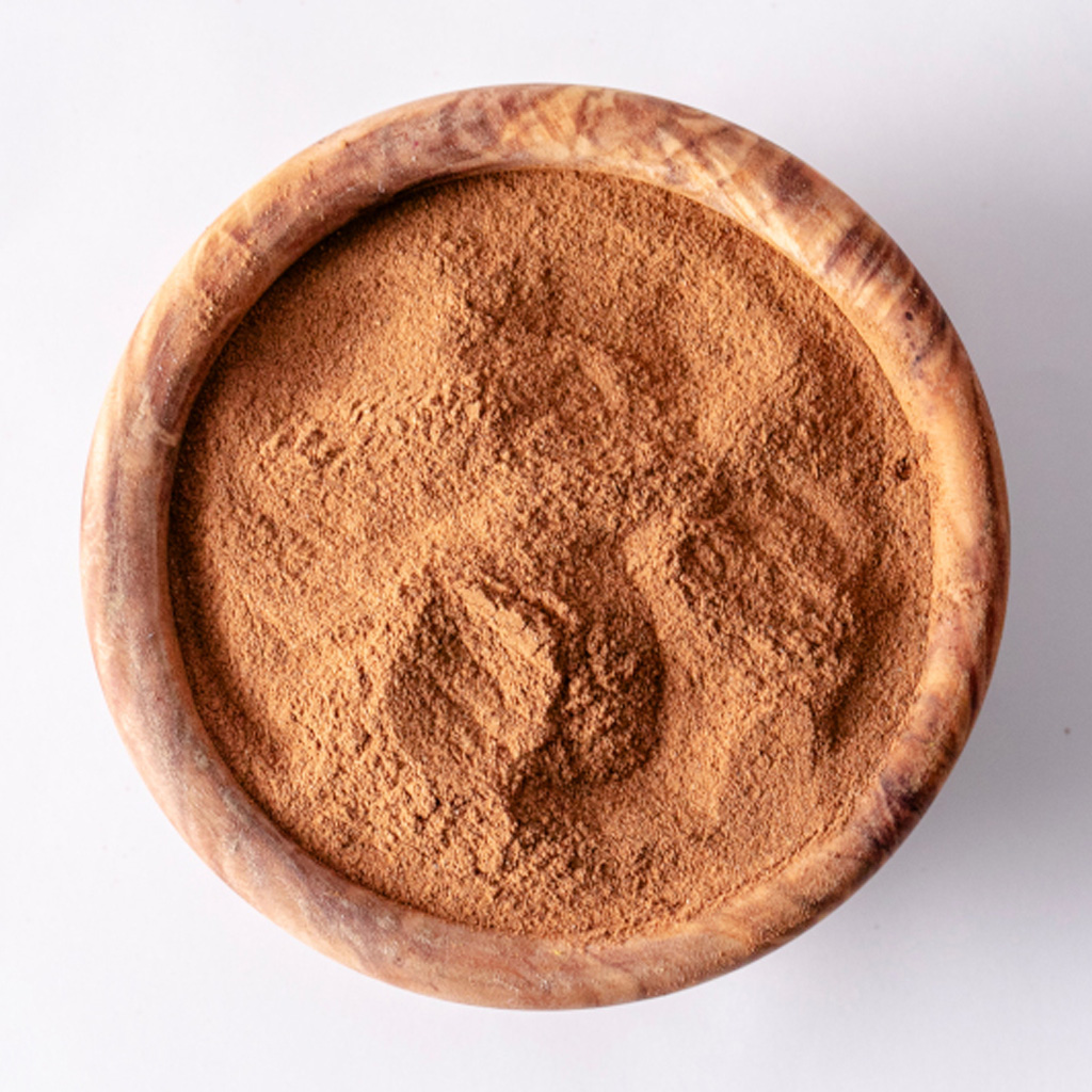 Runde Holzschale mit fein gemahlenem Zimt, braunes Gewürz, Draufsicht