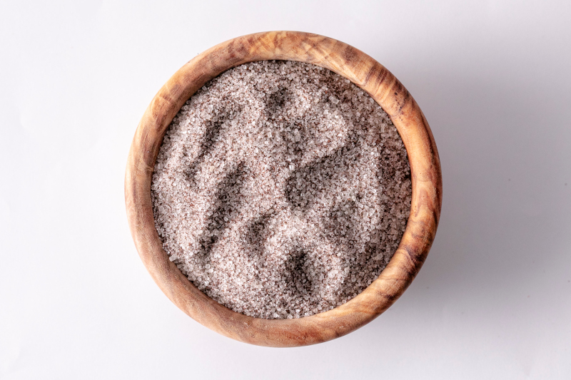 Draufsicht auf grobkörniges rosa Himalaya-Salz in einer runden Holzschale auf hellem Hintergrund