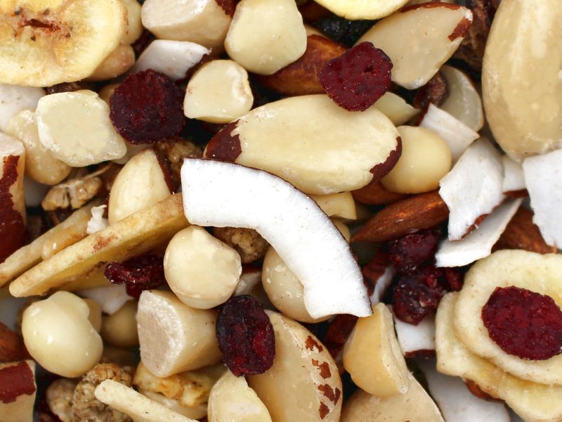 Nahaufnahme eines Snack-Mixes mit Macadamianüssen, Paranüssen, Mandeln, Bananenchips, Kokosstücken und getrockneten Cranberries