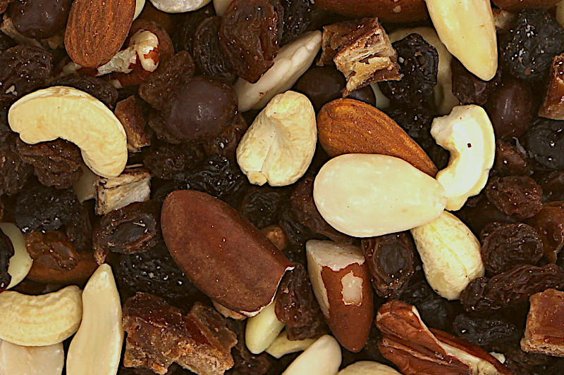 Nahaufnahme eines Nuss-Frucht-Mixes (Studentenfutter) mit Cashews, Mandeln, Paranüssen, Pekannüssen, Rosinen und dunklen Schokotropfen