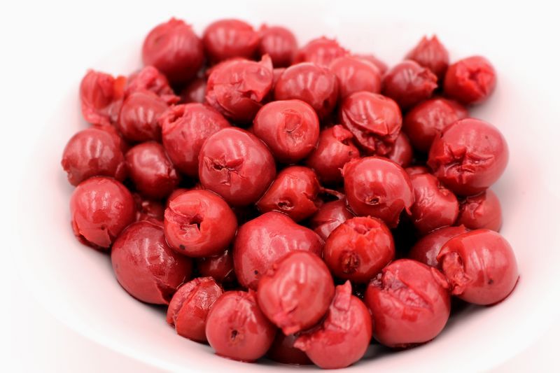 Rote glasierte Cocktailkirschen in einer weißen Schale, glänzend und entsteint, ideal zum Dekorieren von Kuchen, Cocktails und Desserts