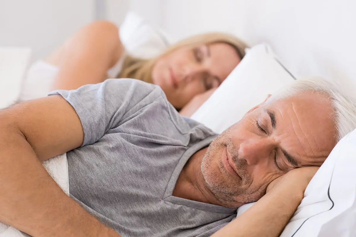 Mann und Frau liegen friedlich schlafend im warmen Schlafzimmer – Geborgenheit und Schlafkomfort in der Nacht.