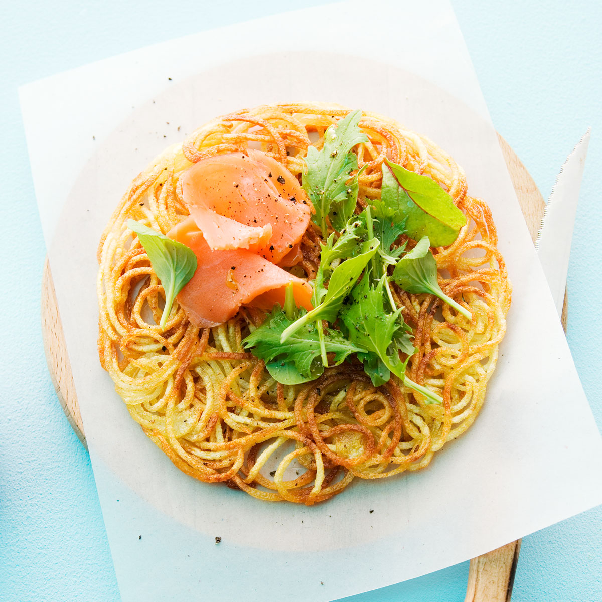 Kartoffelrösti mit Räucherlachs: Knuspriger Rösti aus Kartoffelspaghetti, belegt mit feinem Räucherlachs und serviert mit cremigem Dip. Perfekt zubereitet mit dem Lurch Spiralschneider.