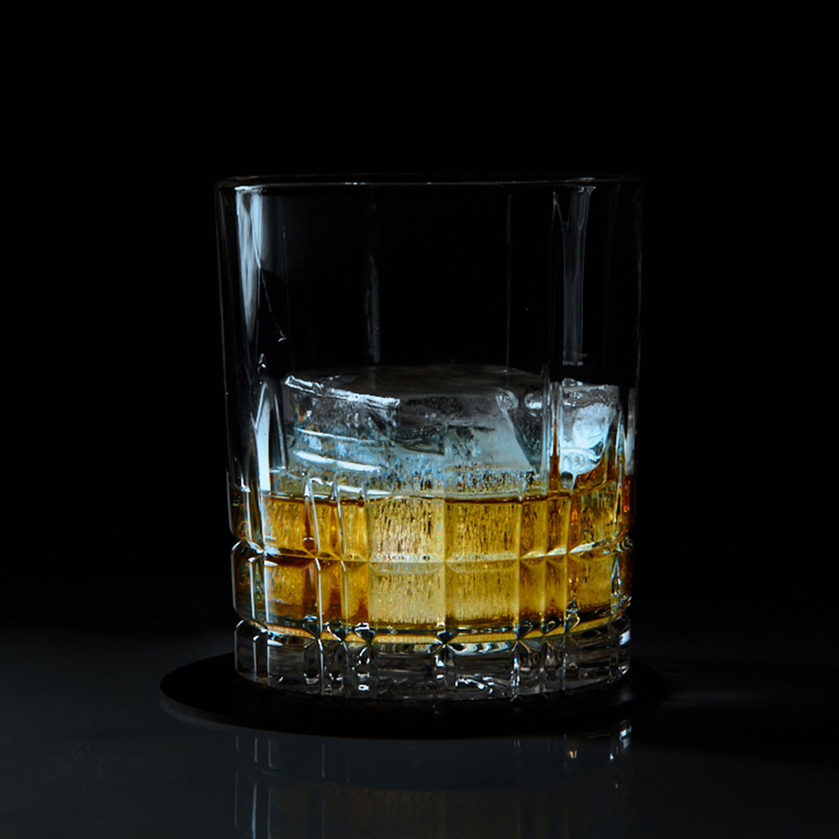 Ein Tumbler mit großem Eiswürfel und edlem Whiskey – klassisch serviert für puren Genuss mit Stil.