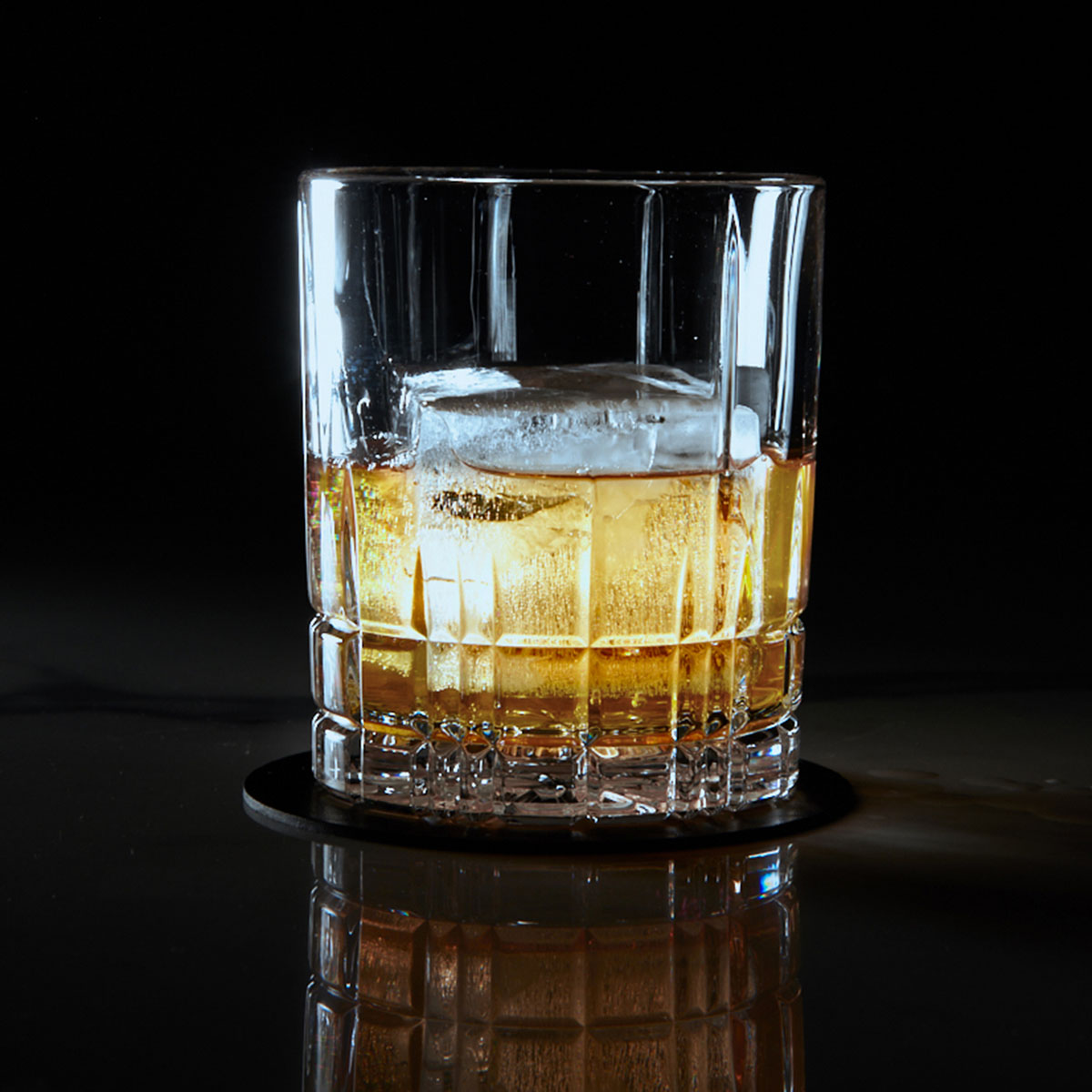 Whiskey in einem Tumbler-Glas mit einem einzelnen großen Eiswürfel – elegant, pur und mit perfekter Balance zwischen Aroma und Kühle.