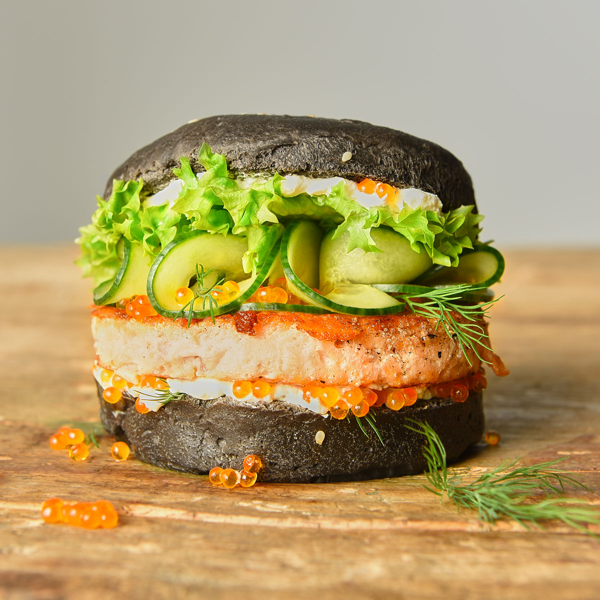 Ausgefallener Lachsburger mit schwarzem Sepiatinten-Bun, frischem Lachsfilet, Lachskaviar, Salat, Gurke, Dill und Crème fraîche für ein edles Geschmackserlebnis. Mit der Lurch Burgerbun-Backform werden die Burgerbrötchen perfekt.