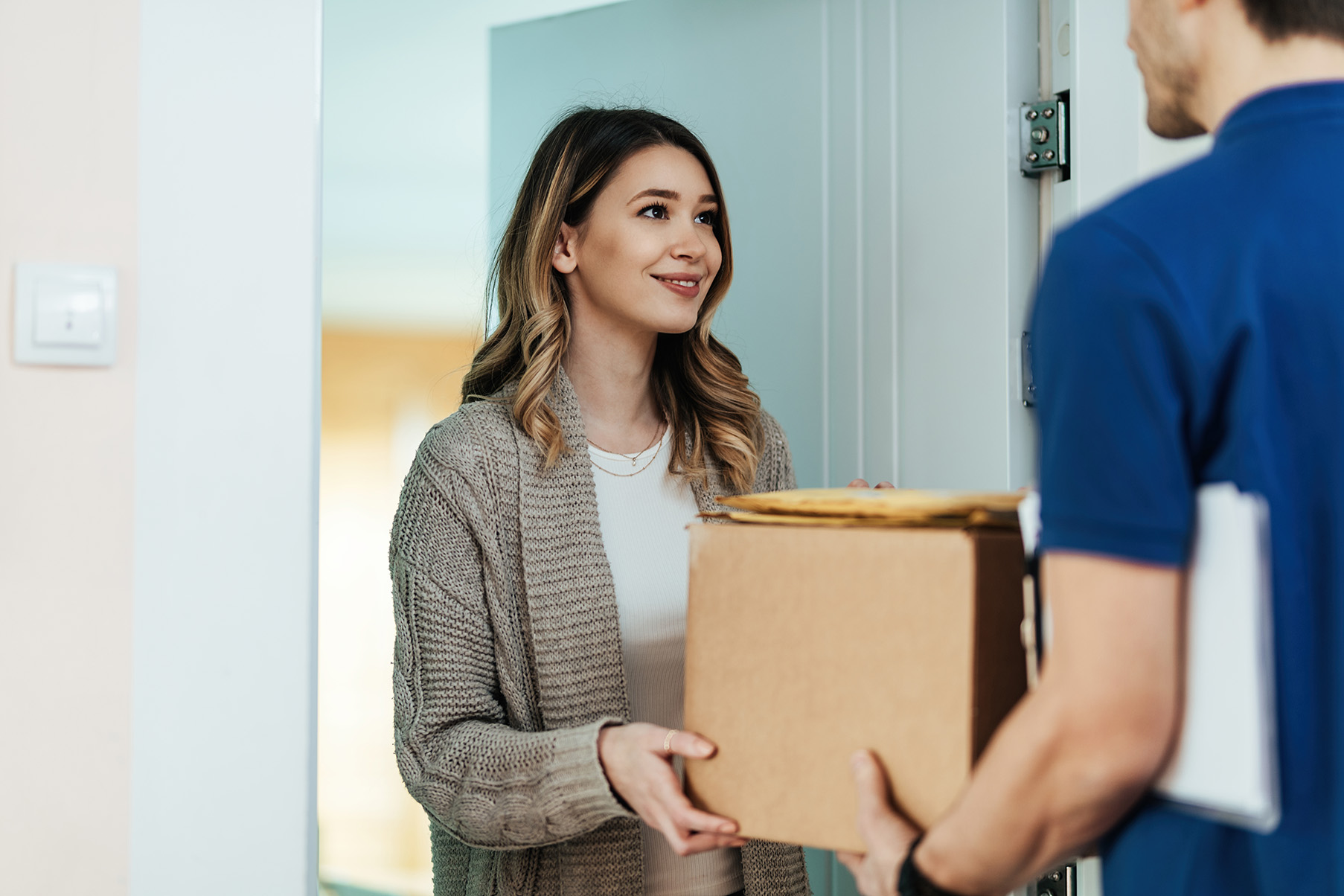 Postbote übergibt einer jungen Frau ein Paket