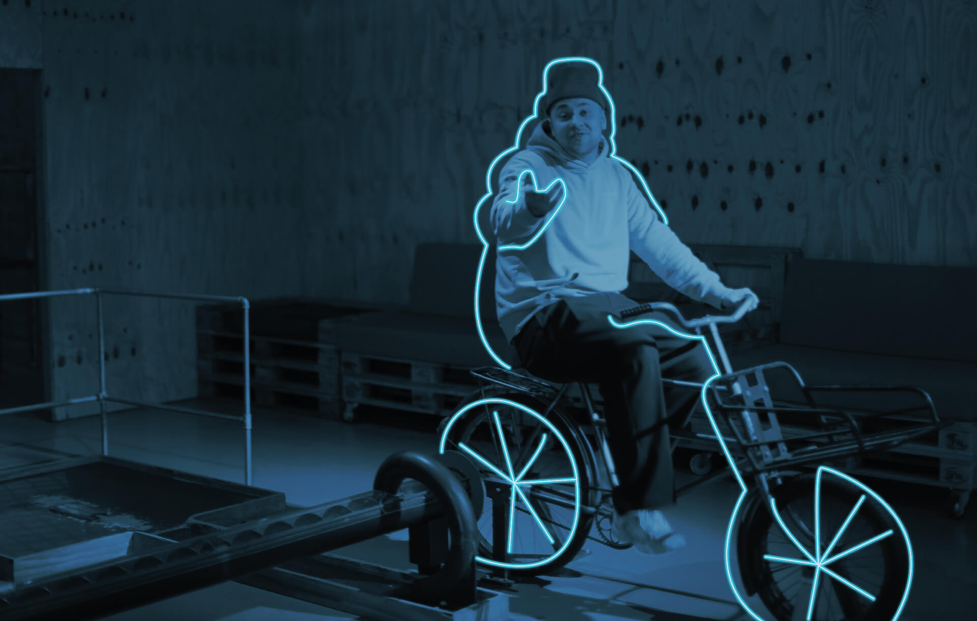 Person auf einem Dreirad, umrandet von einem neonblauen Licht, verleiht dem urbanen Minigolf Spielwitz.