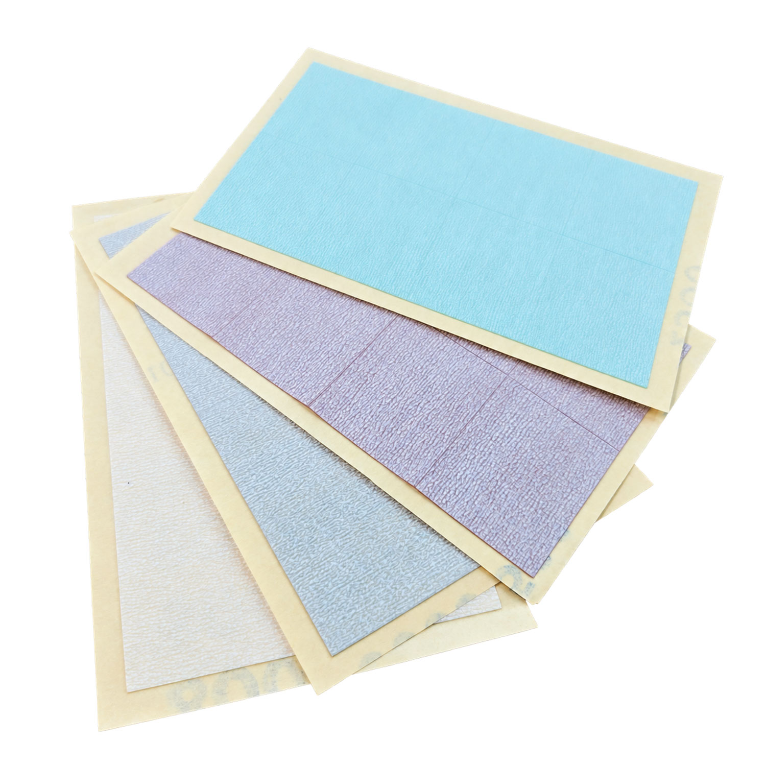 Ein Stapel rechteckiger Klebebögen in verschiedenen Pastellfarben, darunter Hellblau, Lavendel, Grau und gebrochenes Weiß, jeweils mit einer strukturierten Oberfläche und einer hellen Papierrückseite.