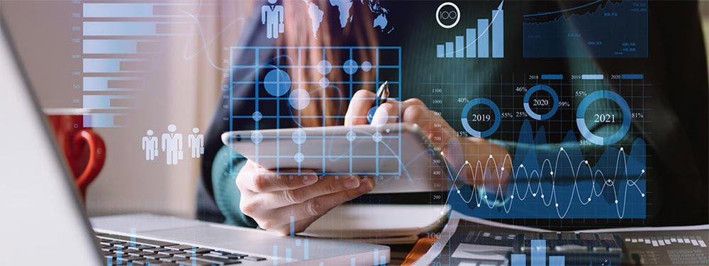 Eine Person verwendet ein Tablet an einem Schreibtisch mit einem Laptop und Dokumenten, überlagert mit digitalen Geschäftsanalysen, einschließlich Balkendiagrammen, Liniendiagrammen und kreisförmigen Datenvisualisierungen.