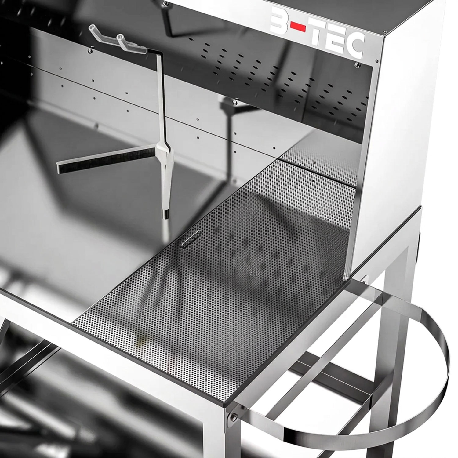 Eine B-TEC-Reinigungsstation aus Edelstahl mit perforierter Arbeitsfläche, einem Spritzpistolenhalter und einem Seitengriff, betrachtet aus einem erhöhten Winkel vor einem weißen Hintergrund.