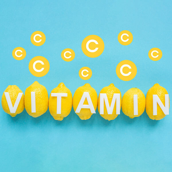 Text: Auf blauem Hintergrund gelbe Zitronen. Buchstaben liegen auf Zitronen. Wort Vitamin. I Punkte, der Buchstabe C. 