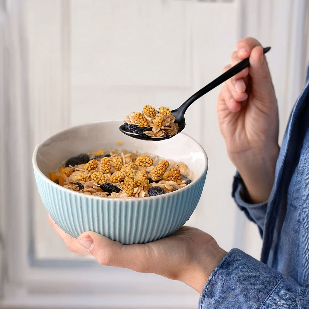 Blaue Schüssel mit Müsli und goldenen Beeren