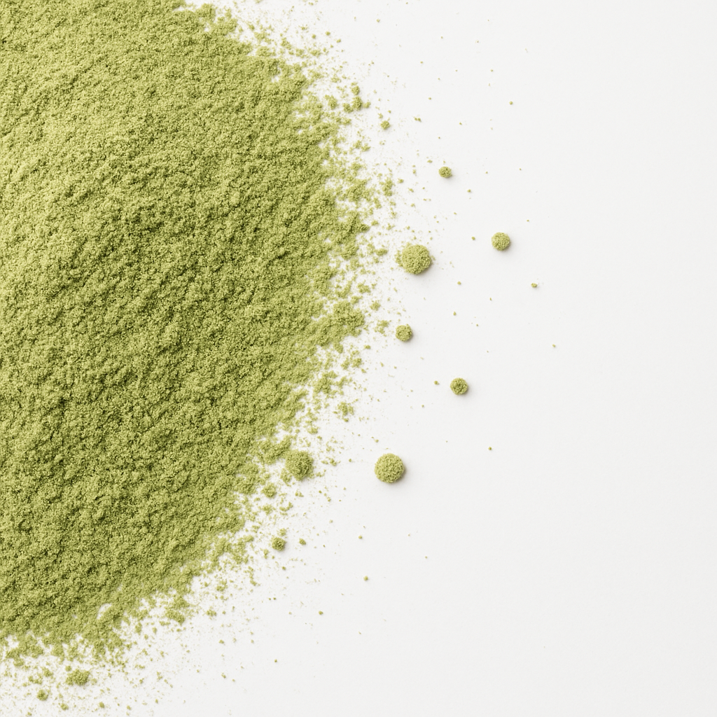 Nahaufnahme von feinem Matcha-Grünteepulver auf einer weißen Fläche, das seine lebendige Farbe und Textur zeigt.