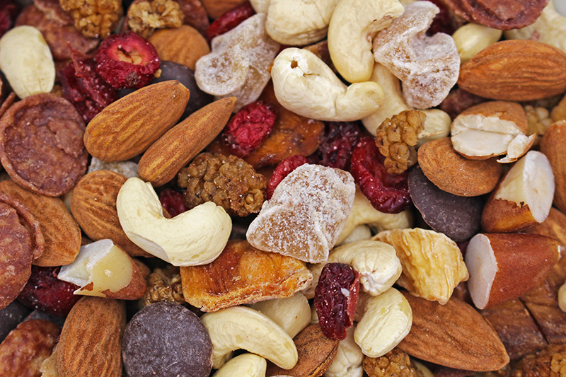 Nærbillede af blandet nødde- og tørret frugtblanding med mandler, cashewnødder, hasselnødder, tørrede tranebær, tørret mango og mørke chokoladestykker.