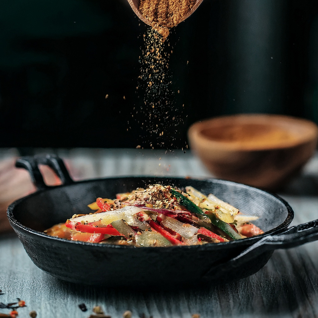 Kochen Sie ein lebendiges Gemüsepfannengericht mit Gewürzen in einer gusseisernen Pfanne