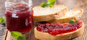 Erdbeermarmelade auf frischen Brotscheiben Glas Erdbeermarmelade mit frischen Brotscheiben