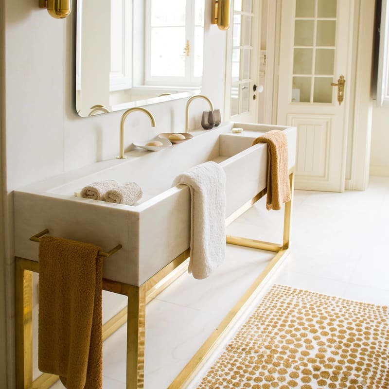 Badezimmer mit Abyss Handtüchern am Waschbecken in warmen Gelb- und Beige-Tönen