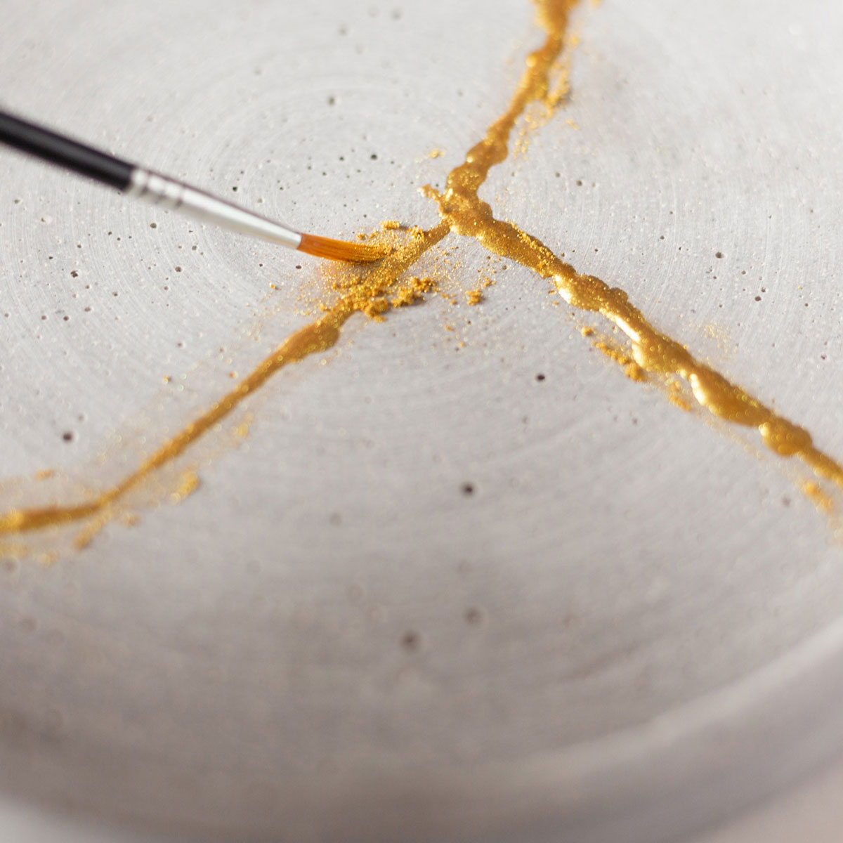 goldene Kintsugi Farbe wird auf einen Teller aufgetragen