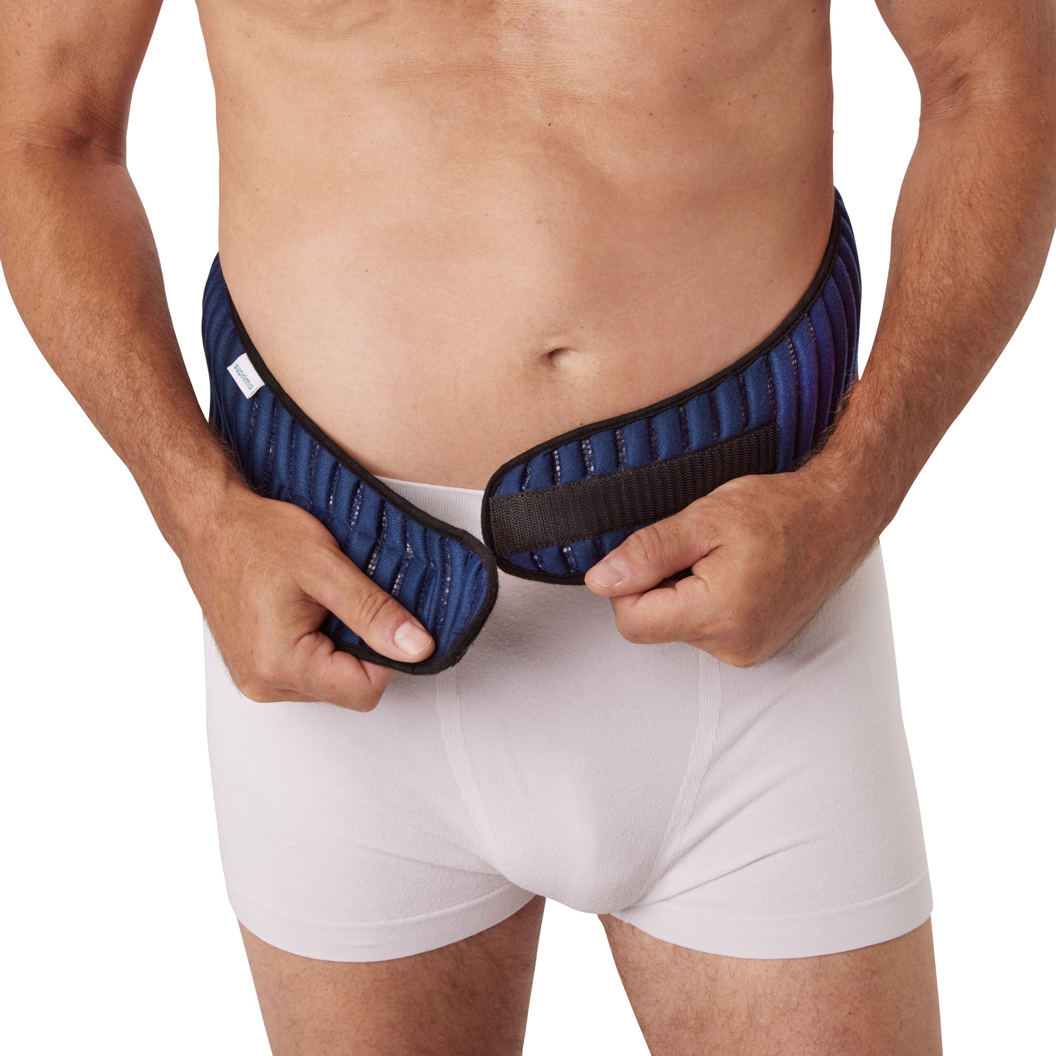 Ein Mann in Unterwäsche zieht einen blauen, gepolsterten Gürtel an, der um seine Taille gewickelt ist. Der Gürtel zeigt eine strukturierte Oberfläche und wird gerade geschlossen.