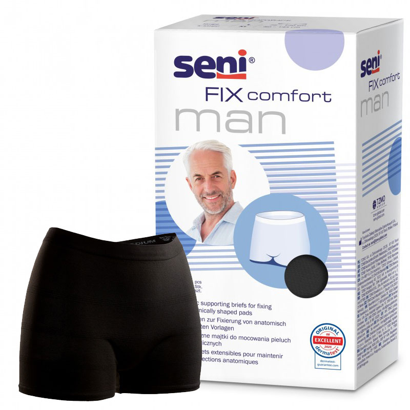 Schwarze Fixierunterwäsche für Männer liegt vor einer Verpackung. Die Box zeigt einen lachenden Mann, Produktinformationen sind sichtbar. Die Unterwäsche dient zur Befestigung anatomisch geformter Einlagen.