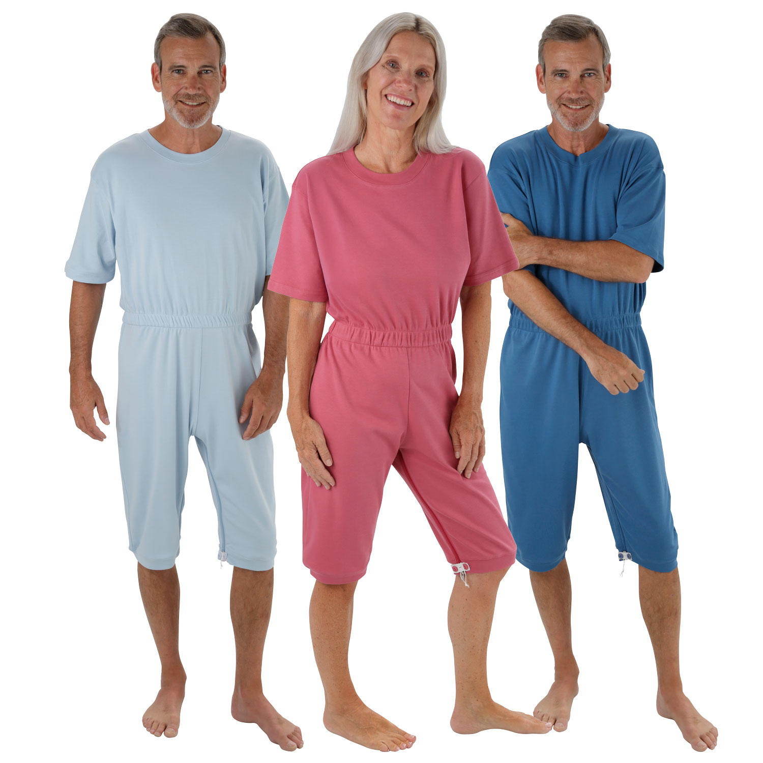 Drei Personen stehen nebeneinander, jeder trägt einen einteiligen Schlafanzug in unterschiedlichen Farben (blau, pink, himmelblau). Die Kleidung hat kurze Ärmel und hosenähnliche Enden. Sie stehen auf einem weißen Hintergrund.