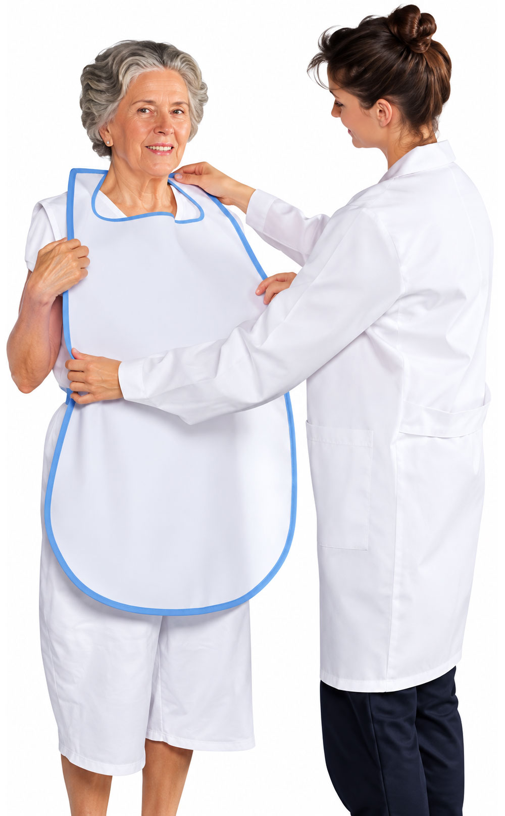 Eine ältere Frau trägt ein weißes Lätzchen mit blauer Umrandung, während eine Pflegerin ihr hilft, es anzulegen. Beide Personen sind in hellen, praktischen Outfits gekleidet und lächeln.