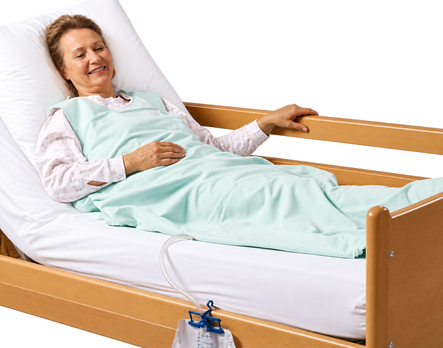 Eine lächelnde Frau liegt in einem Pflegebett, bedeckt mit einer mintgrünen Decke. Neben ihr ist ein Auffangbehälter mit einem Schlauch sichtbar. Der Hintergrund ist hell und einfach.