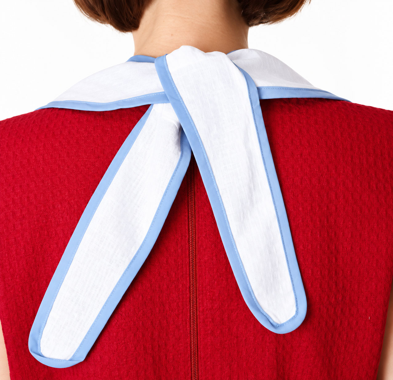 Ein rotes Kleid mit strukturiertem Stoff wird von einem weißen Kragen mit blauen Akzenten ergänzt. Der Kragen ist hinten in einer Schleife gebunden, die locker über die Schultern fällt.