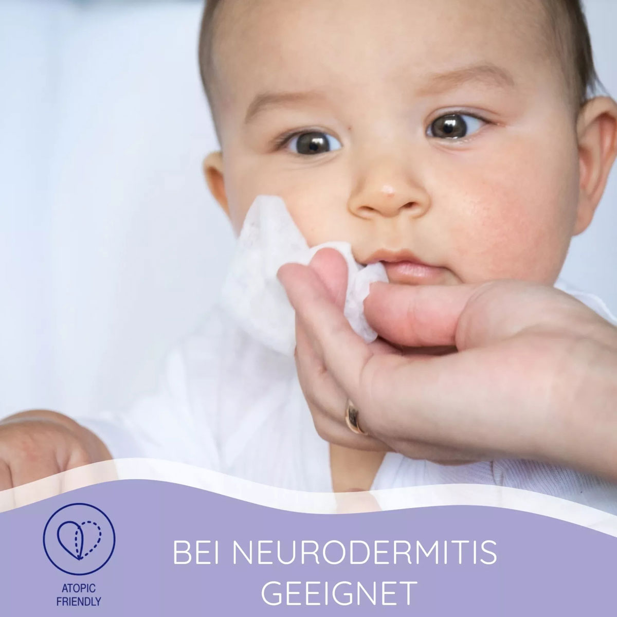 Ein Baby wird sanft mit einem Pflegepad an der Wange gereinigt. Die Hand eines Erwachsenen hält das Pad. Im Hintergrund ist ein heller, neutraler Farbton. Text: -BEI NEURODERMITIS GEEIGNET- und -ATOPIC FRIENDLY-.